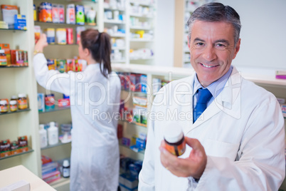 Smiling pharmacist holding a box of pills