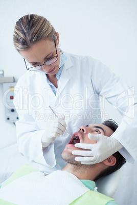 Female dentist examining mans teeth