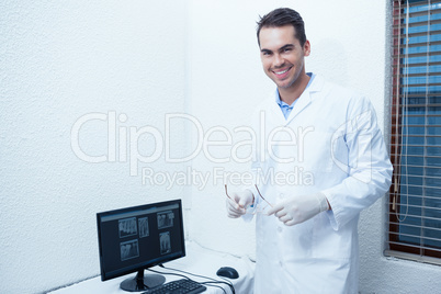 Smiling male dentist with computer monitor