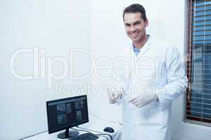 Smiling male dentist with computer monitor