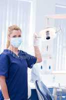 Dentist in mask holding light