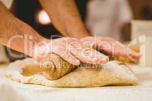 Baker rolling dough at a counter