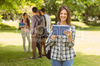 Smiling student with a shoulder bag and using tablet computer