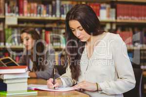 Concentrating pretty brunette student writing in notepad
