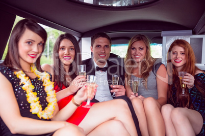 Happy friends drinking champagne in limousine