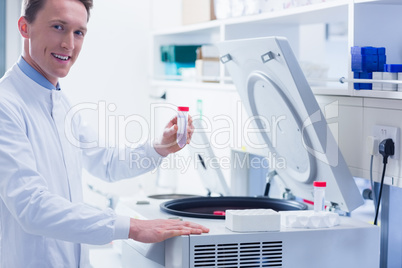 Smiling chemist holding a test tube looking at camera