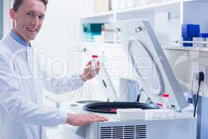 Smiling chemist holding a test tube looking at camera