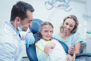 Dentist examining girls teeth with assistant