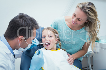 Dentist examining girls teeth with assistant