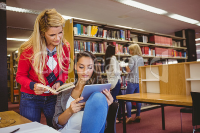 Students using a digital tablet with classmates behind