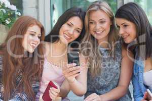 Happy students sitting in a row texting