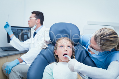 Female dentist examining girls teeth