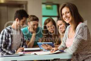 Smiling friends sitting studying and using tablet pc