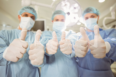 Team of surgeons looking at camera showing thumbs up