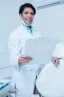 Smiling female dentist holding clipboard