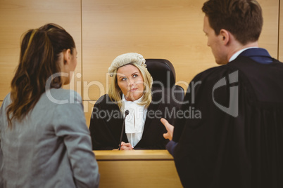 Judge wearing dress and wig listening lawyers