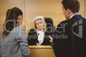 Judge wearing dress and wig listening lawyers