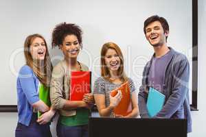 Students standing and smiling at camera holding notepads