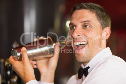 Handsome barman smiling at camera making a cocktail