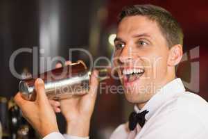 Handsome barman smiling at camera making a cocktail