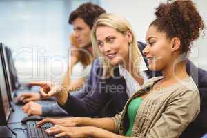 Attractive teacher talking to her student in computer class