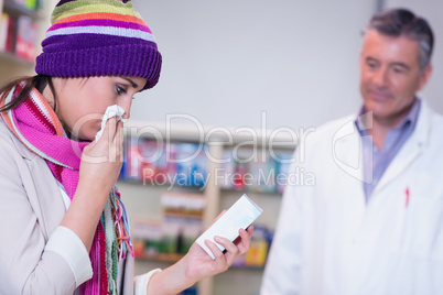 Sick woman with scarf and colorful hat holding a box of drug