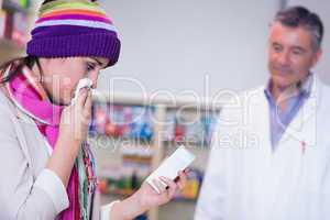 Sick woman with scarf and colorful hat holding a box of drug