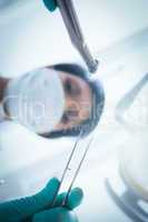 Female dentist in surgical mask holding dental tools