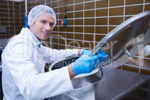 Smiling man in lab coat opening the lid of the machine