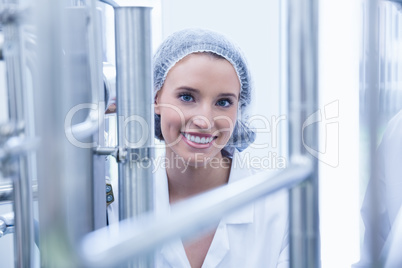 Portrait of a smiling scientist behind metal pipe