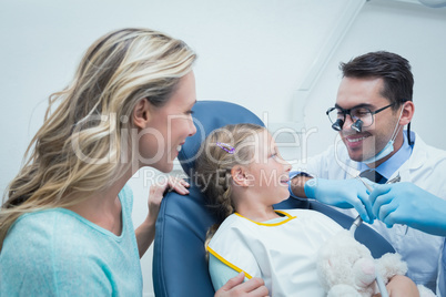 Dentist examining girls teeth with assistant