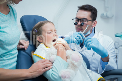 Dentist examining girls teeth with assistant