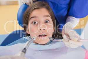 Dentist and his dental assistant examining a terrified young pat