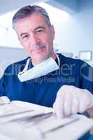 Dentist picking up tool and smiling at camera