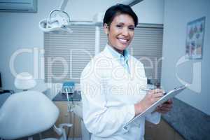 Smiling female dentist holding clipboard