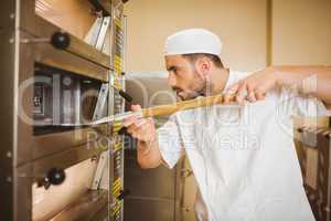 Baker taking bread out of oven