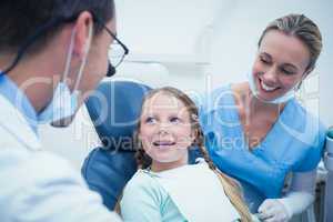 Dentist with assistant examining girls teeth