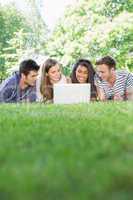 Happy students using laptop outside