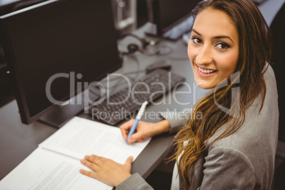 Smiling student sitting at desk writing on notepad