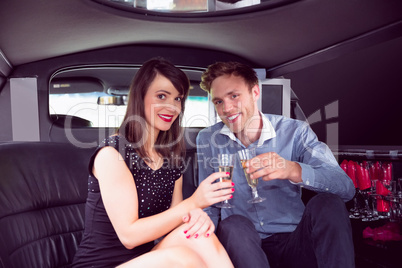 Happy friends drinking champagne in limousine