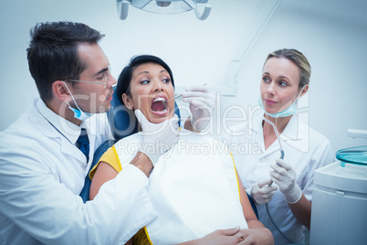 Male dentist with assistant examining womans teeth