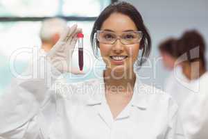 Pretty science student smiling and showing vial