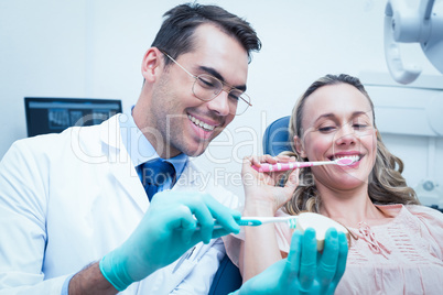 Male dentist teaching woman how to brush teeth