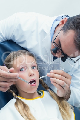 Male dentist examining girls teeth