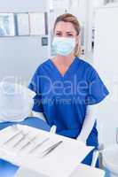 Dentist in mask behind tray of tools