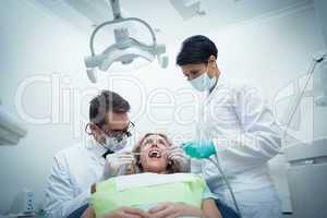 Dentist with assistant examining womans teeth