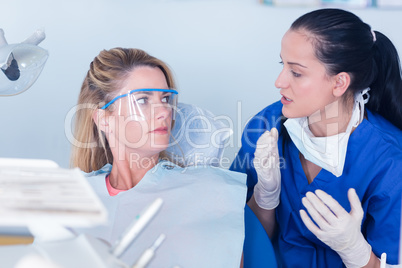 Dentist talking with patient in chair