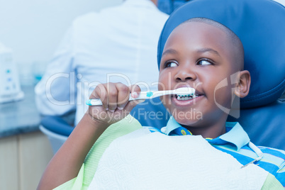 Boy brushing teeth in the dentists chair