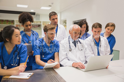 Medical students and professor using laptop