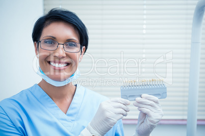 Smiling female dentist holding teeth model